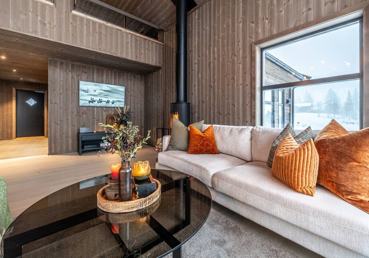 A modern living room with a sofa, a glass coffee table, and a fireplace.