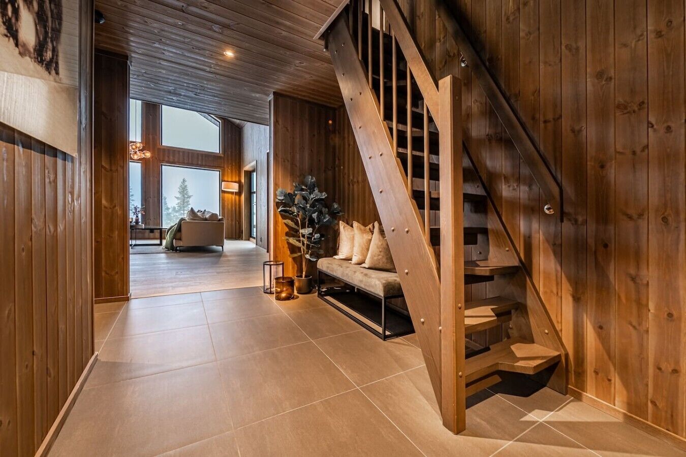 A wooden interior with a staircase, a sofa, and a plant.