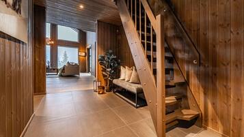 A wooden interior with a staircase, a sofa, and a plant.