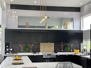 Una cocina moderna con armarios negros, una isla central y una lámpara colgante.