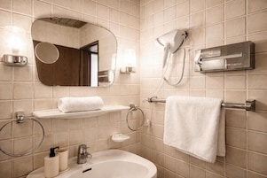 Un baño con lavamanos, espejo, toallero y secador de pelo.