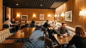 A restaurant with wooden walls, multiple seating areas, and tables with chairs. - REDBERRY Hotel - Düsseldorf - Neuss (Neuss)