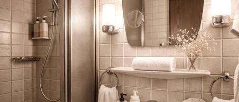 A bathroom with a shower, a sink, a mirror, and a towel rack.