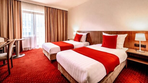 A hotel room with two beds, a desk, and a chair. - REDBERRY Hotel - Düsseldorf - Neuss (Neuss)