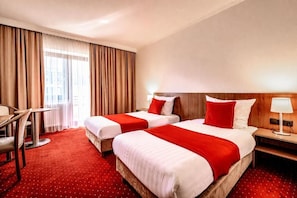 A hotel room with two beds, a desk, and a chair.