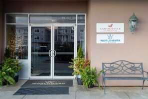 A hotel entrance with a glass door, a bench, and two signs on the wall.