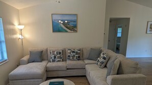 A living room with a sectional sofa, a round coffee table, and a painting on the wall.