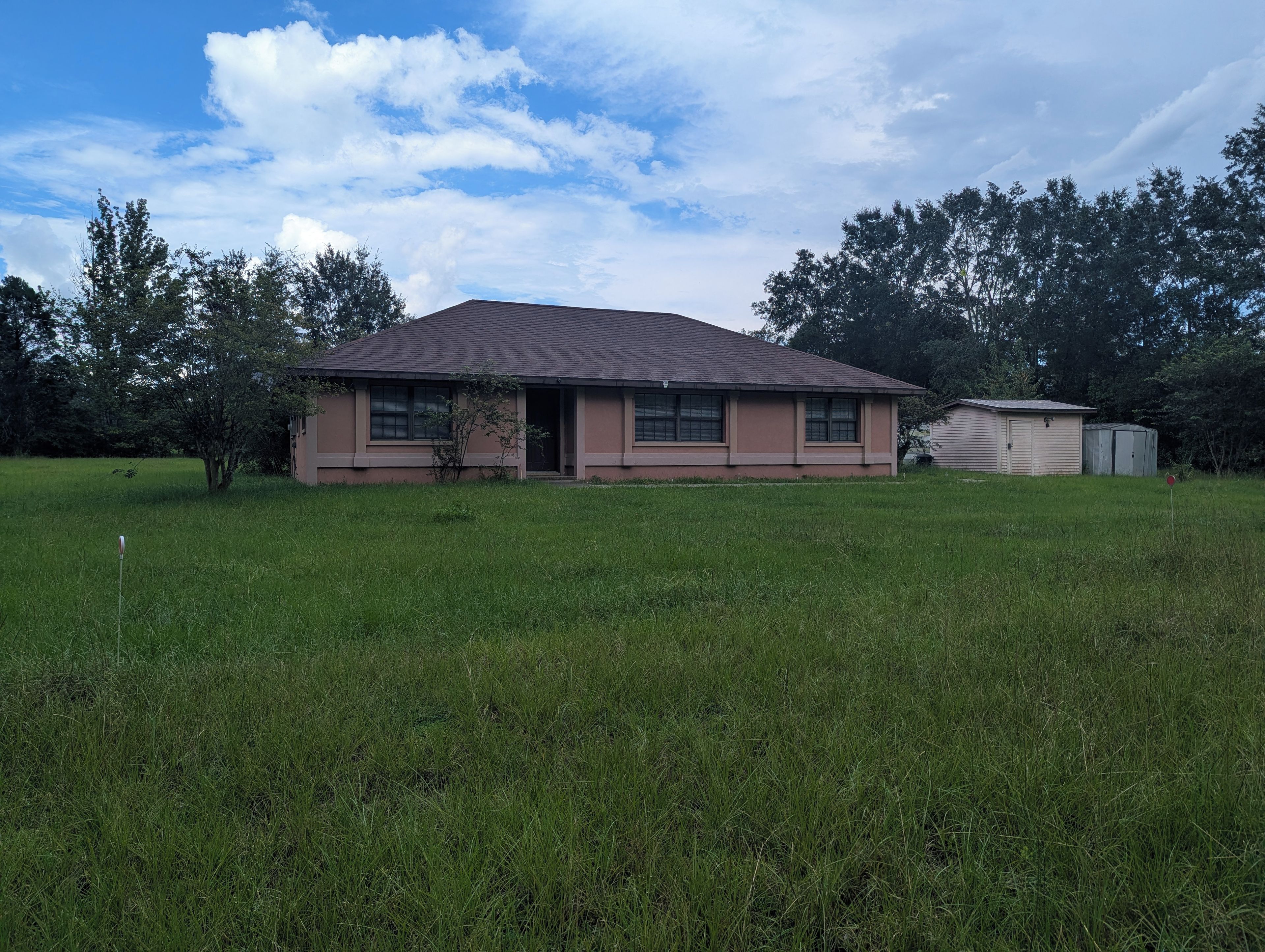 A single-story house with a flat roof, a small attached garage, and a well-maintained lawn.