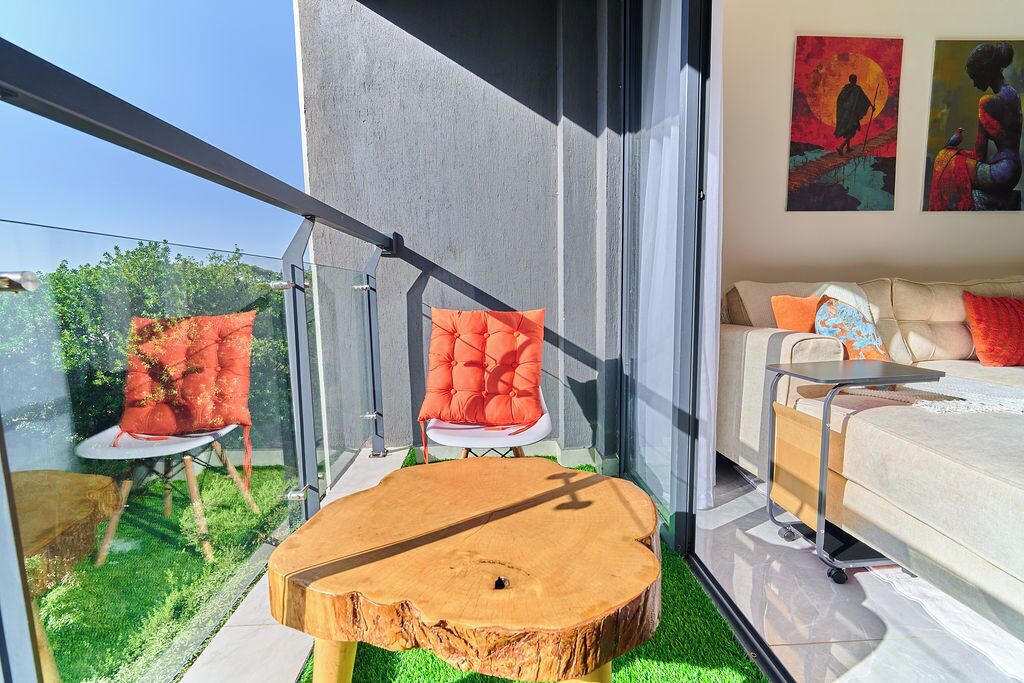 A modern living room with a glass balustrade, a wooden coffee table, and a sofa with cushions.