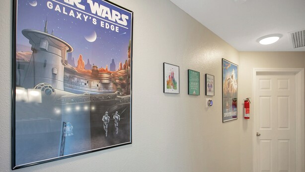 Ein Flur mit einem großen Star Wars Poster, gerahmten Bildern und einem Feuerlöscher.