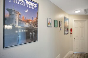 A hallway with a large Star Wars poster, framed pictures, and a fire extinguisher. - Disney Area · Themed Family Home · Pool · Parking (Davenport)