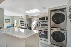 A kitchen with a central island, a microwave, oven, and a stacked washer and dryer. - Disney-Themed Family Home, Pool and Courts, Minutes to the Parks (Davenport)