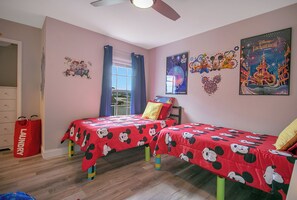 A bedroom with two beds, a window with blue curtains, and Disney-themed decorations on the walls. - Disney Area · Themed Family Home · Pool · Parking (Davenport)