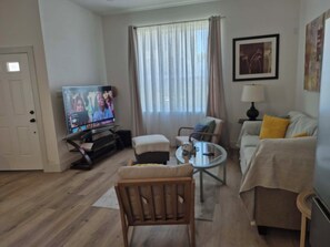 Ein Wohnzimmer mit Fernseher, einer Couch, einem Couchtisch und einem Sessel.