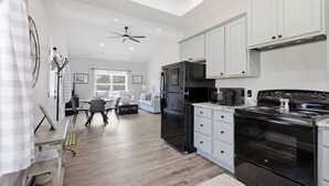A spacious kitchen with a black refrigerator, microwave, and stove, white cabinets, and a dining area with a table and chairs.