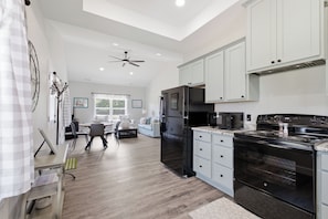 A spacious kitchen with a black refrigerator, microwave, and stove, white cabinets, and a dining area with a table and chairs.