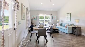 A spacious living room with a dining area, a blue sofa, and a ceiling fan.