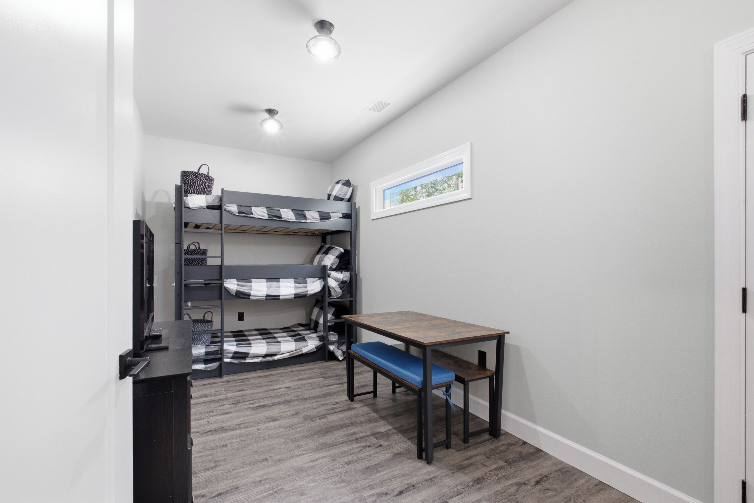 A bunk bed with a desk and chair, a framed picture on the wall, and a door on the right.