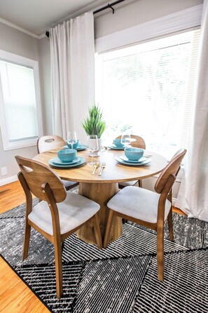 A dining area with a round table, blue tableware, and chairs with cushioned seats.