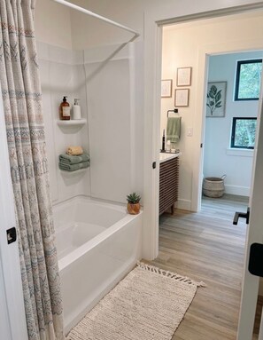 A bathroom with a bathtub, shower, and a small shelf with toiletries. - Fabulous 2-bedroom apartment in Traverse City-Monthly Rental (Traverse City)