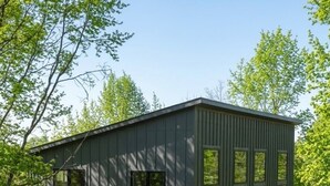 A modern two-story building with a flat roof, large windows, and a gravel driveway. - Fabulous 2-bedroom apartment in Traverse City-Monthly Rental (Traverse City)