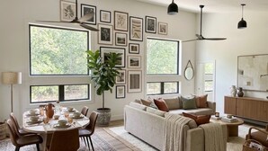 A modern living room with a dining area, large windows, and a variety of framed pictures on the wall. - Fabulous 2-bedroom apartment in Traverse City-Monthly Rental (Traverse City)