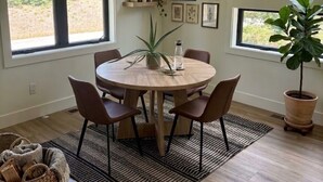 A dining area with a round table, chairs, a potted plant, and framed artwork on the wall. - Fabulous 2-bedroom apartment in Traverse City-Monthly Rental (Traverse City)