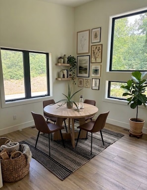 A dining area with a round table, chairs, a potted plant, and framed artwork on the wall. - Fabulous 2-bedroom apartment in Traverse City-Monthly Rental (Traverse City)