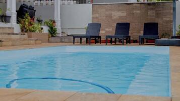 Une piscine avec des chaises longues et des plantes en pot.