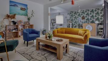 Un salon avec un canapé, des fauteuils, une table basse et un tableau au mur.
