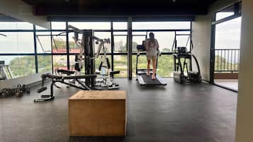 A gym with exercise equipment, a wooden box, and a person using a treadmill.