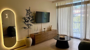 A modern living room with a flat-screen TV, a large mirror, a potted plant, a wooden cabinet, and a round coffee table. - Cozy Apt near San Salvador Historic Center/Pool+Gym (San Salvador)