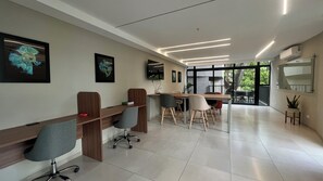 Un moderno spazio ufficio con lunghe scrivanie in legno, sedie ergonomiche e un'ampia finestra che offre vista sull'esterno.