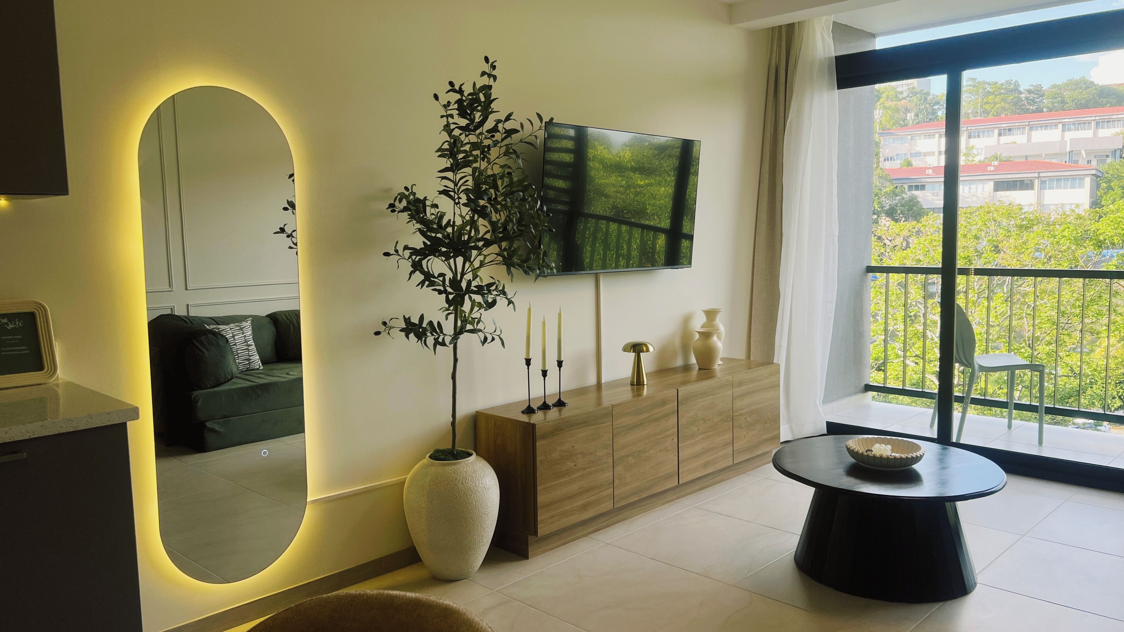 A modern living room with a large TV, a wooden cabinet, a large vase, and a round table.