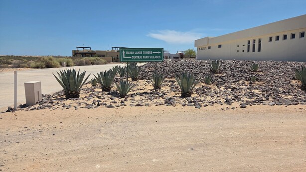 Wüstenlandschaft mit einem Schild, das die Richtung zu Mayan Lakes Towers und Central Park Villages anzeigt.