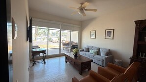 Ein geräumiges Wohnzimmer mit Sofa, Couchtisch und Deckenventilator.