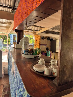 A kitchen counter with a tray of food items, a coffee maker, and a person in the background. - VAI Bungalow with beach access, kayaks, and a relaxation area by the lagoon (MOOREA Haapiti)
