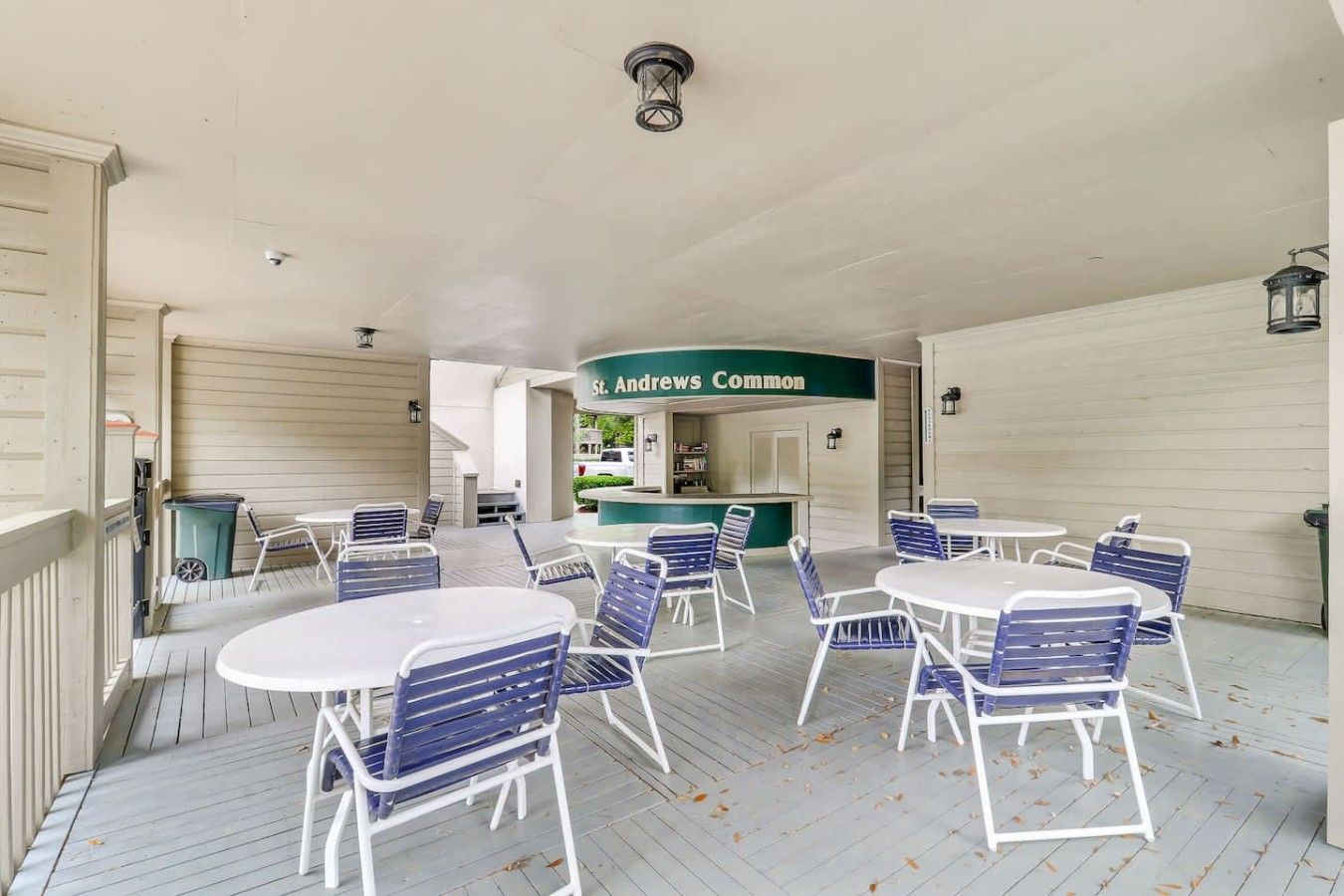 A covered outdoor seating area with tables and chairs, a counter with a sign reading 'St. Andrews Common,' and a ceiling with a light fixture.