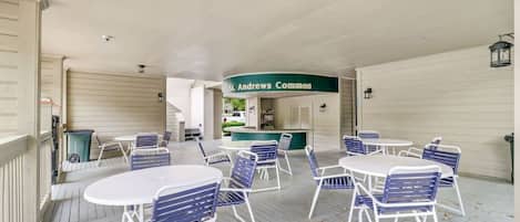 A covered outdoor seating area with tables and chairs, a counter with a sign reading 'St. Andrews Common,' and a ceiling with a light fixture.