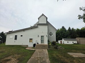 A white single-story building with a gabled roof, a front door, and a small circular window.