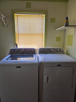 A laundry room with two Maytag washers and dryers, a window with blinds, and a shelf with a bottle. - Beautiful Viking "Long Hall" lodge with AC in charming Waubay SD. (Waubay)
