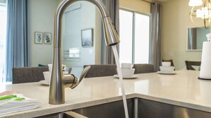 A modern kitchen with a stainless steel faucet, a countertop, and a sink. - 4BR Storey Lake Resort Near Disney Private Pool (Kissimmee)