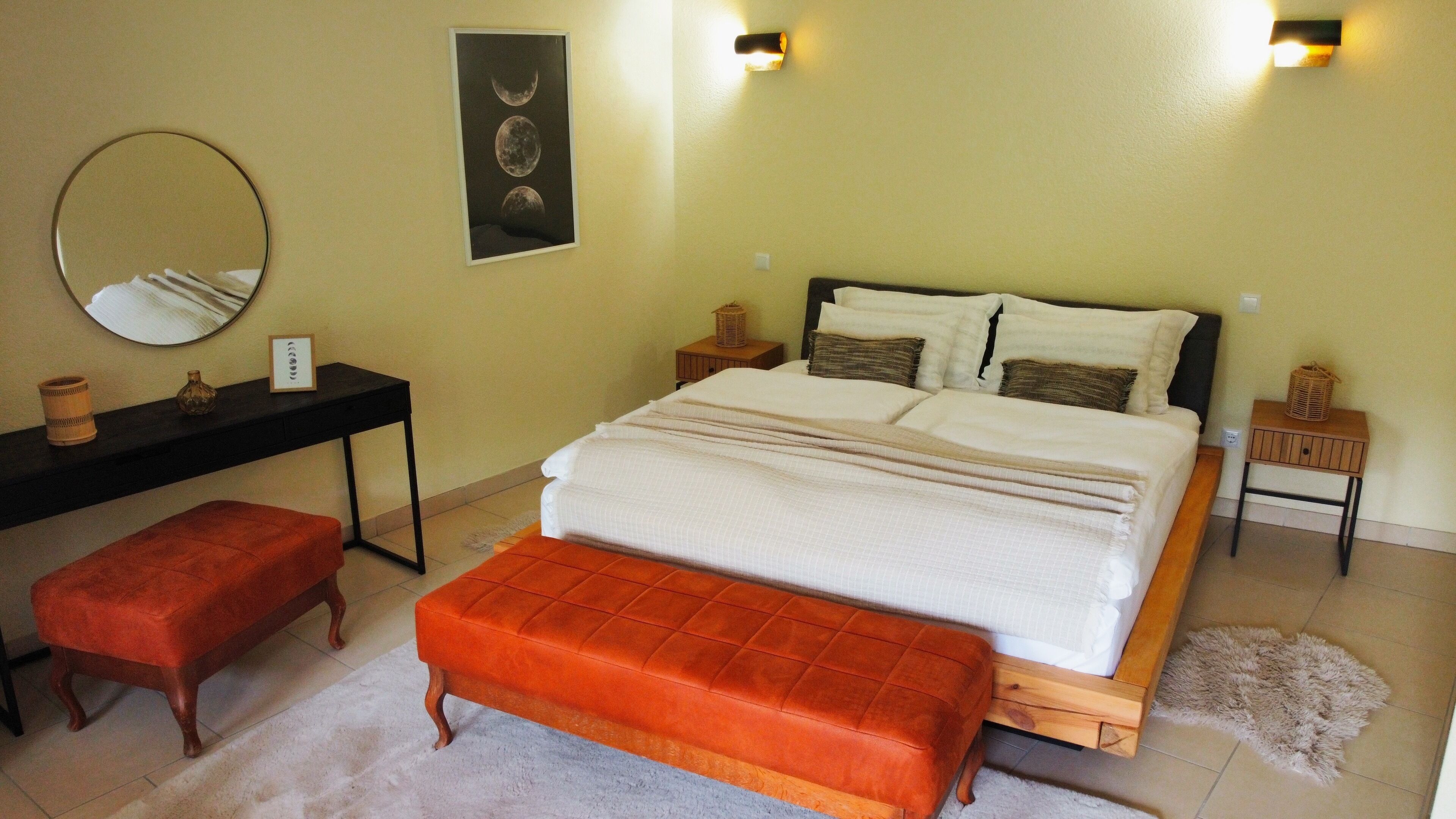 Une chambre à coucher avec un lit, un bureau, un miroir et un banc.