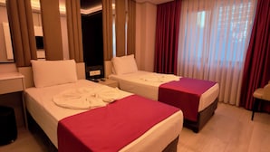 Habitación de hotel con dos camas, un escritorio y una silla.