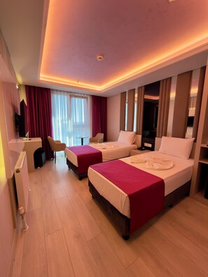 Habitación de hotel con dos camas, un escritorio, una silla y una televisión.