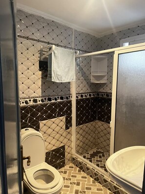 Ein Badezimmer mit Toilette, Duschkabine und Waschbecken.