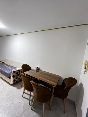 Ein kleines Zimmer mit einem Bett, einem Holztisch und zwei Stühlen.