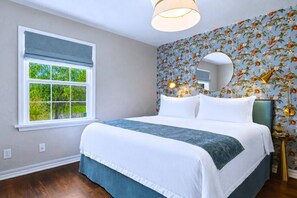 A bedroom with a large bed, a window with a view of greenery, and a floral wallpaper. - Clementine Cottage - By Fairgrounds, Kid-Friendly - Stay Smiley Rentals (Oklahoma City)