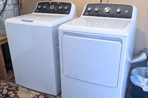 Two front-loading washing machines in a room with a patterned carpet. - Clementine Cottage - By Fairgrounds, Kid-Friendly - Stay Smiley Rentals (Oklahoma City)