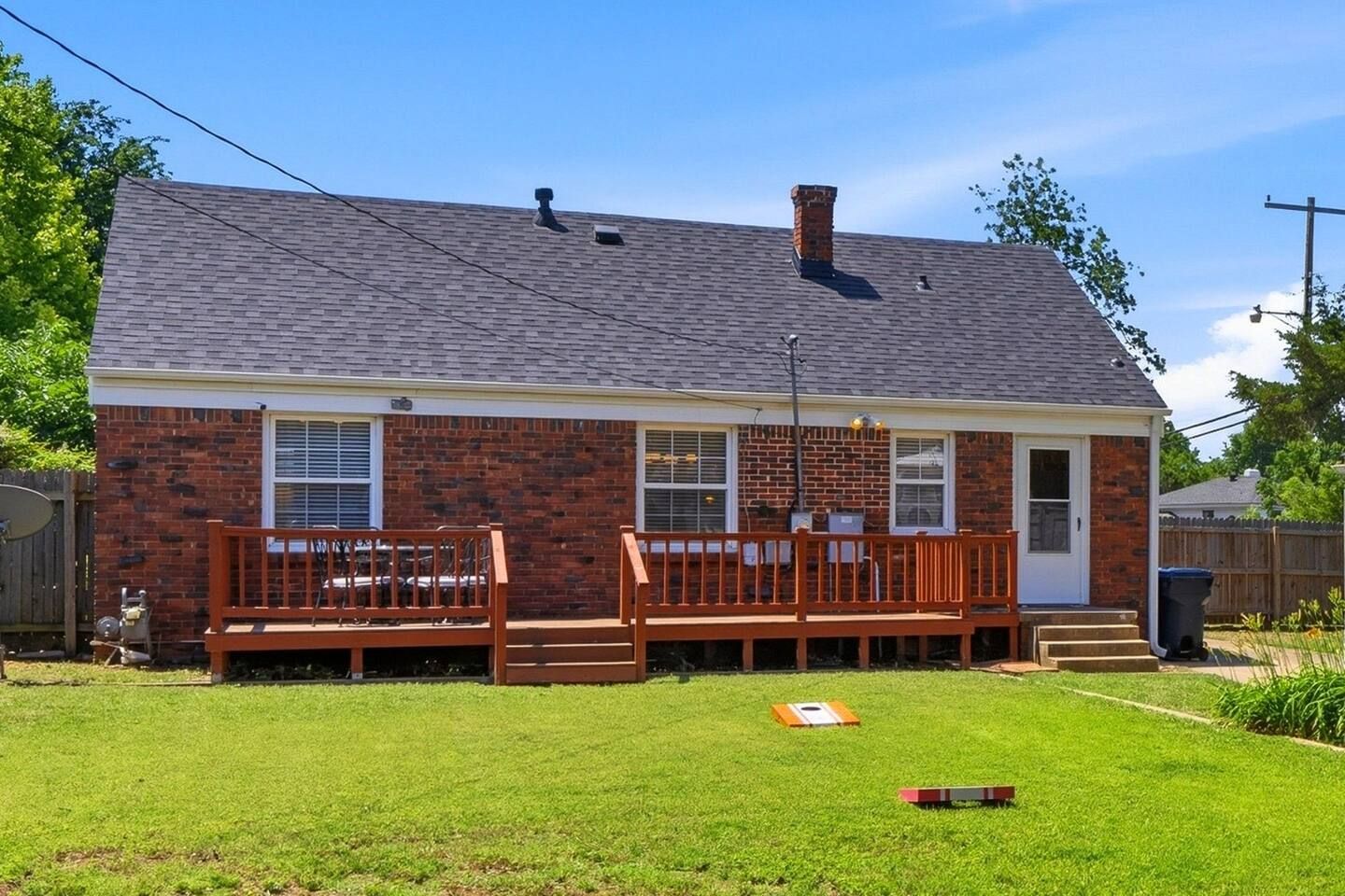 A single-story brick house with a front deck and a small front yard.